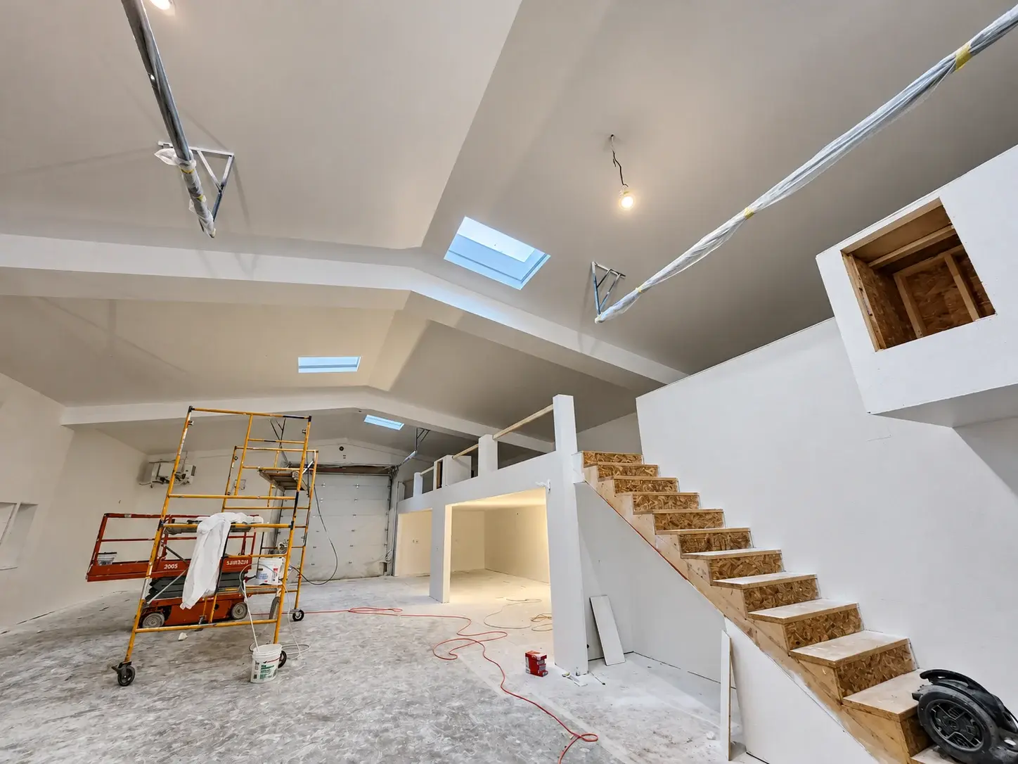 Drywall walls and skylit ceiling around an open staircase